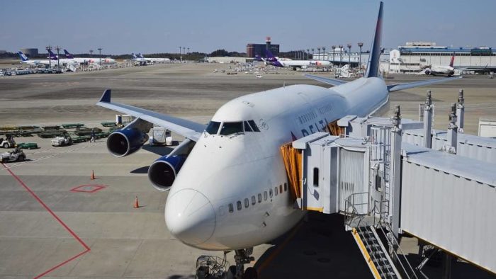 Un avión estacionado junto a una terminal del aeropuerto, conectado por un corredor.