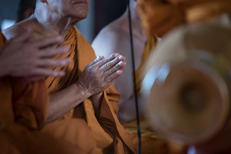 Buddhist monks in orange robes praying at a funeral.