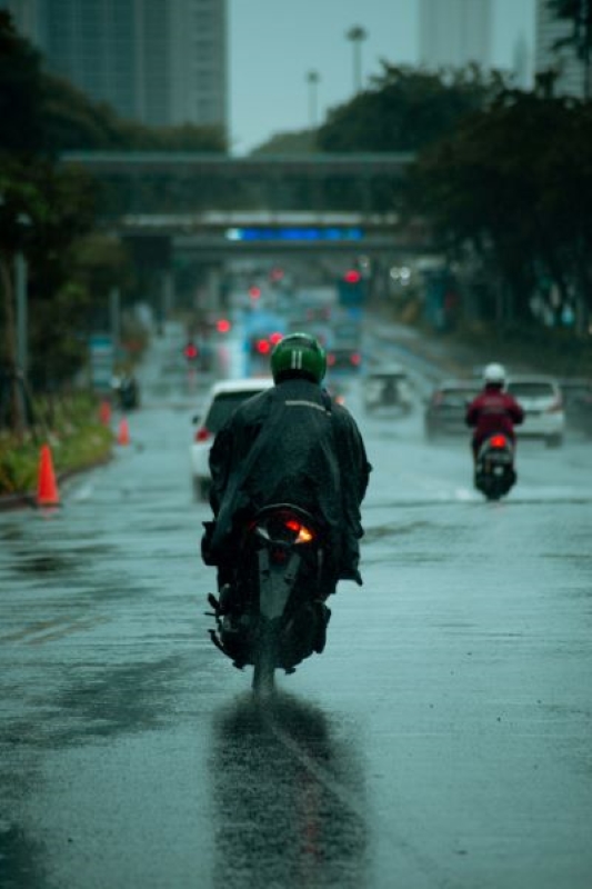 Motorcycle rider on a wet Bangkok road at dusk