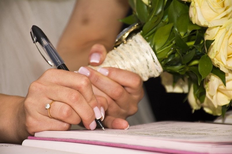 Bride signing a marriage document with a pen