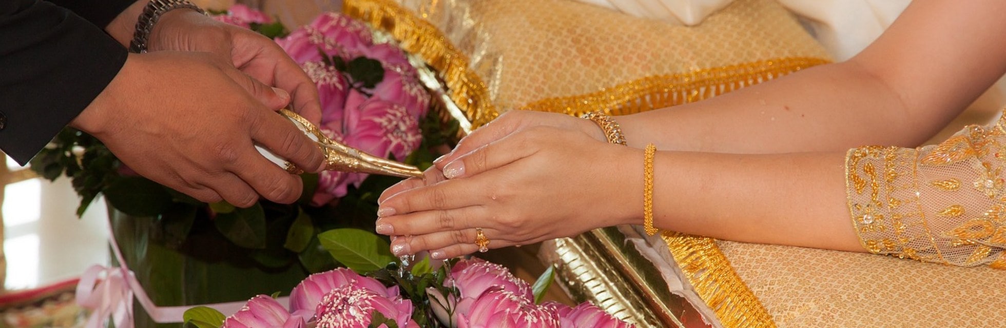Thai wedding water pouring ceremony over the hands of the bride and groom