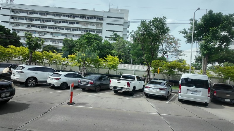 Exterior of a Thai government office complex with parked cars