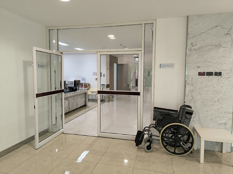 Hospital entrance doors in Bangkok with a wheelchair parked to the side