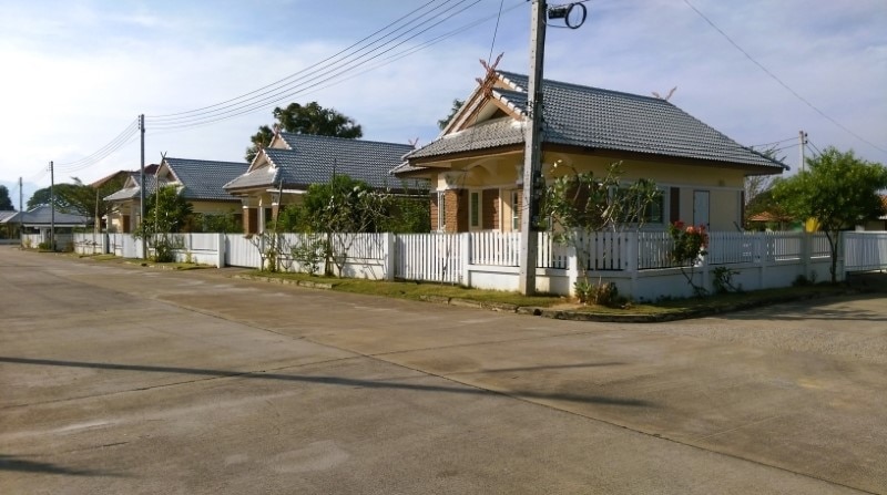 Single-storey houses behind a white fence in a Chiang Mai housing project