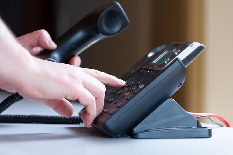 Hand dialing a phone to call an insurance complaints hotline