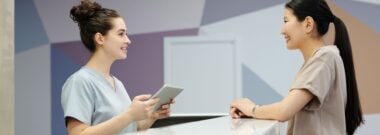 Clinic reception staff reviewing details with a patient at the counter