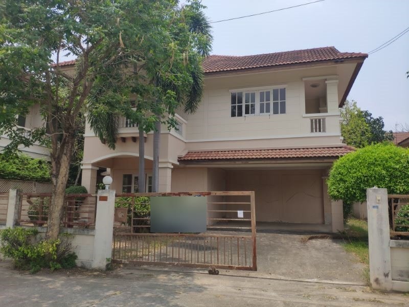 Two-storey house with a for-sale sign on the gate in a Thai housing estate