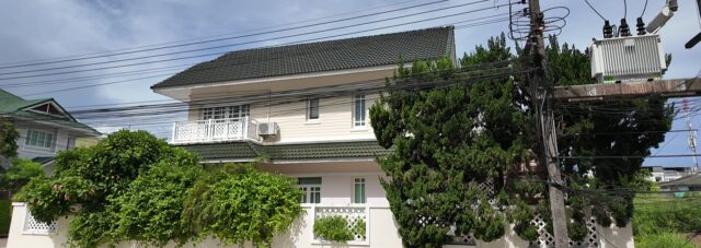 Detached family house behind a white wall in a housing estate in Rayong, Thailand