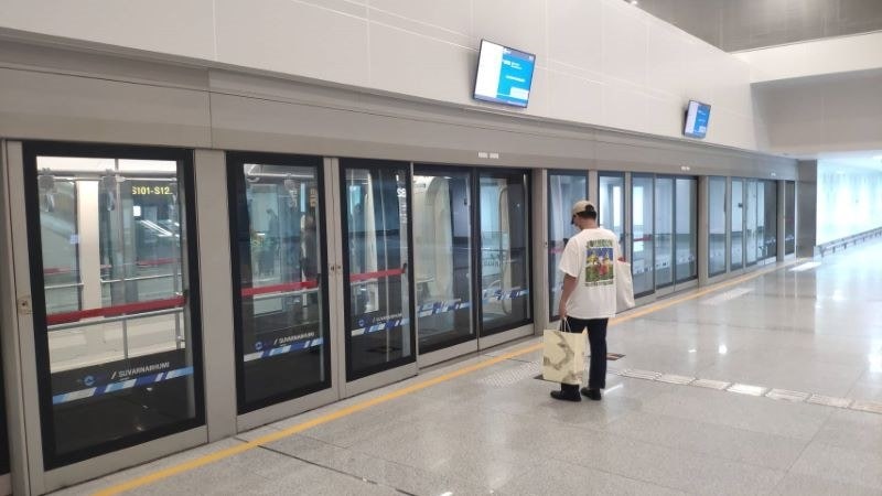 A passenger waiting at an Airport Rail Link platform with glass screen doors, Bangkok