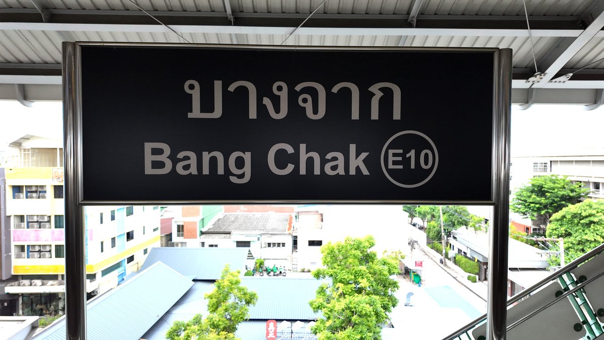 Bang Chak BTS station sign (E10) in Thai and English, with the low-rise sois of Bang Chak below the platform