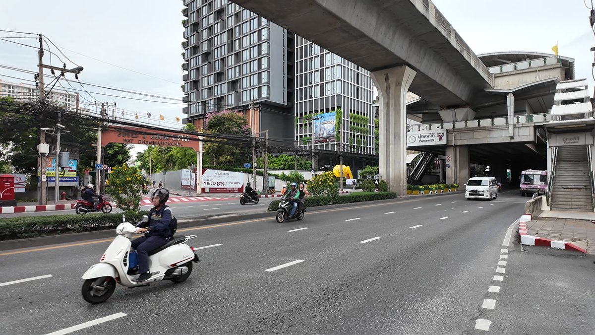 BTS Punnawithi station over Sukhumvit Road in Bangkok, with motorbikes and new condo towers