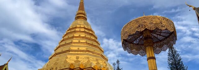 Golden chedi and umbrella at Wat Phra That Doi Suthep in Chiang Mai under a blue sky