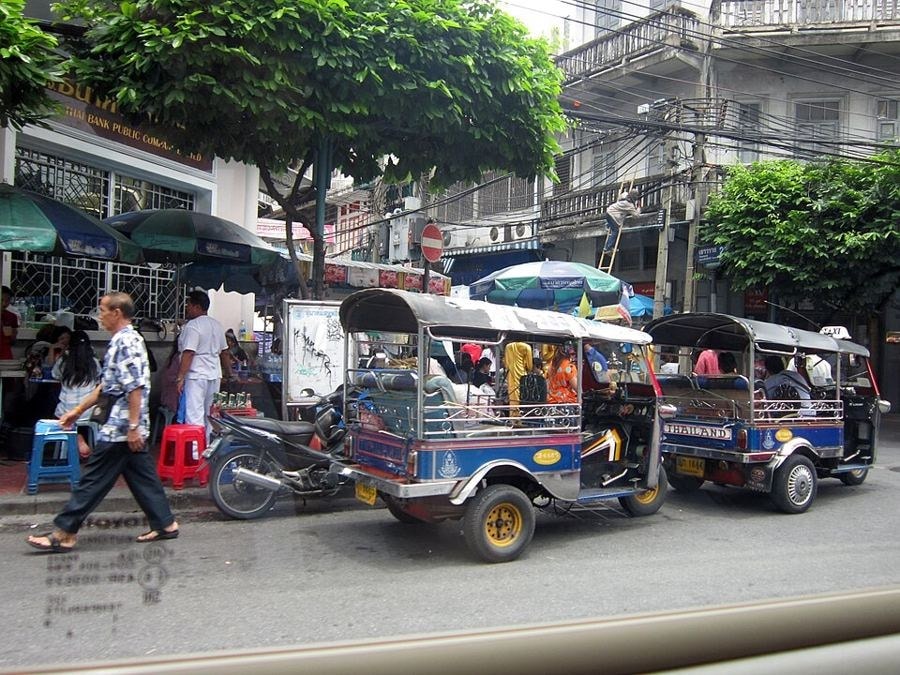 Tuk-tuks parked beside street food stalls and shophouses in the Khlong Toei area of Bangkok