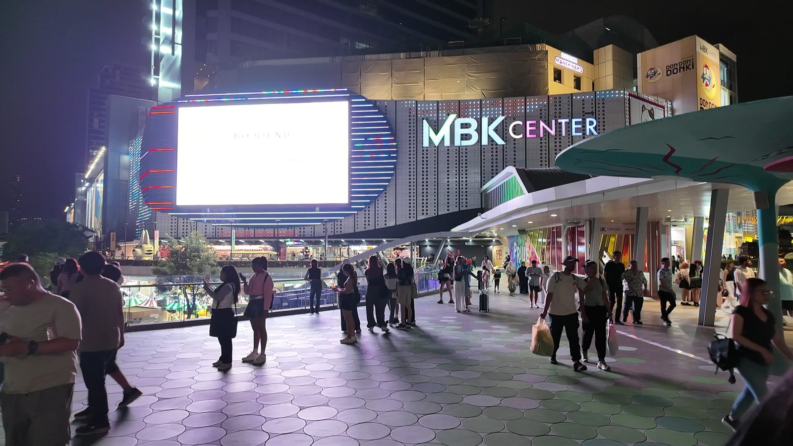 People walking across the plaza outside MBK Center in Bangkok at night