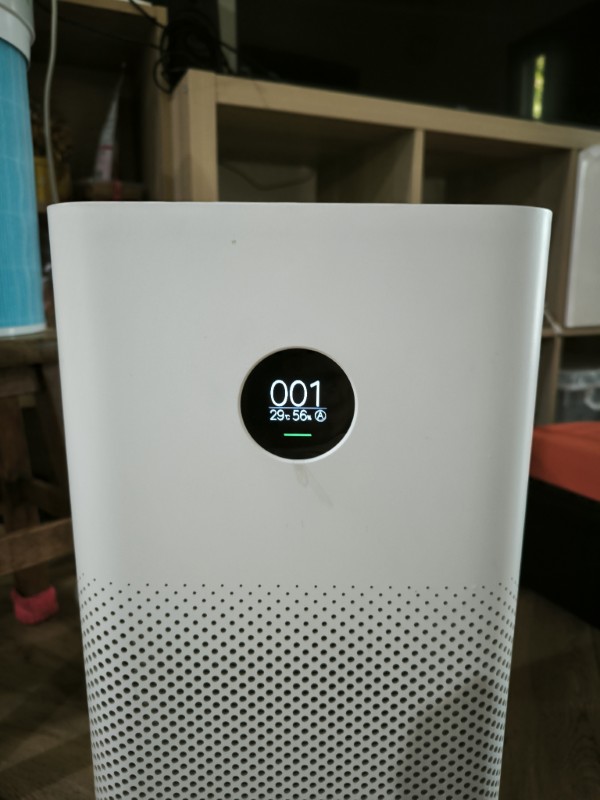 White Xiaomi air purifier with a round display showing a PM2.5 reading of 001