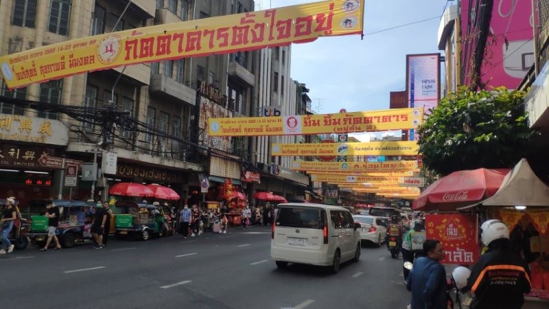 Yaowarat Road in Bangkok's Chinatown by day, with shop banners strung across the street