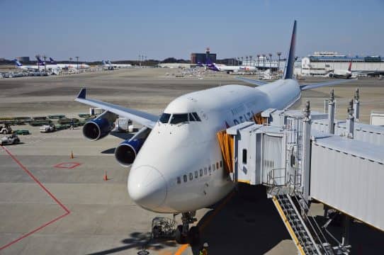 An airplane parked next to an airport terminal, connected by a corridor.